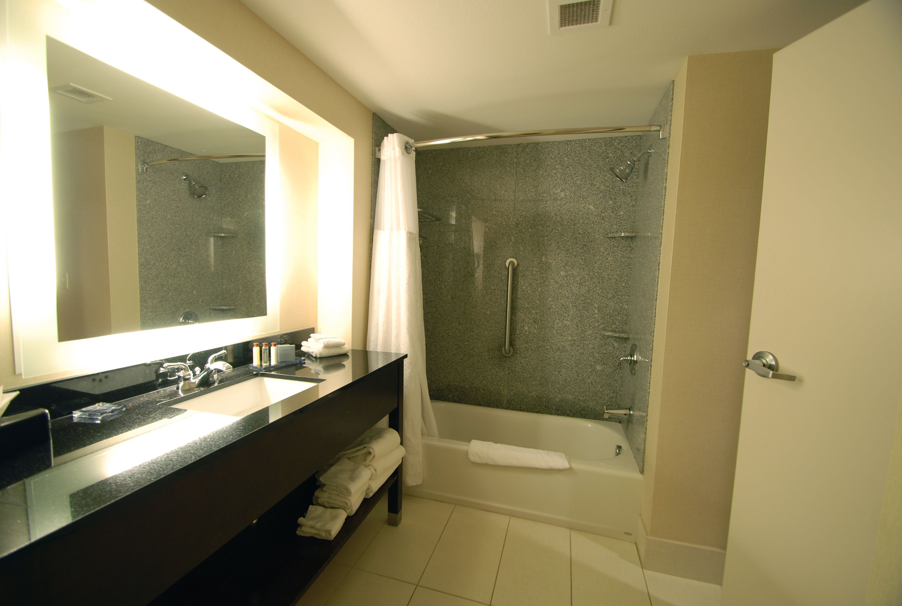 Une salle de bain moderne avec un grand miroir, un lavabo, une baignoire et une douche.