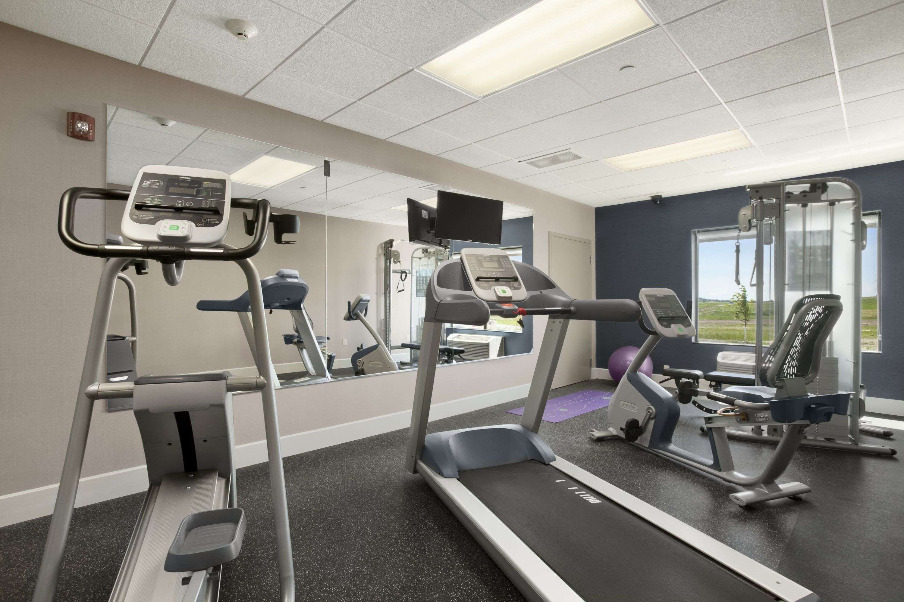 A gym with treadmills, elliptical machines, and weight equipment.