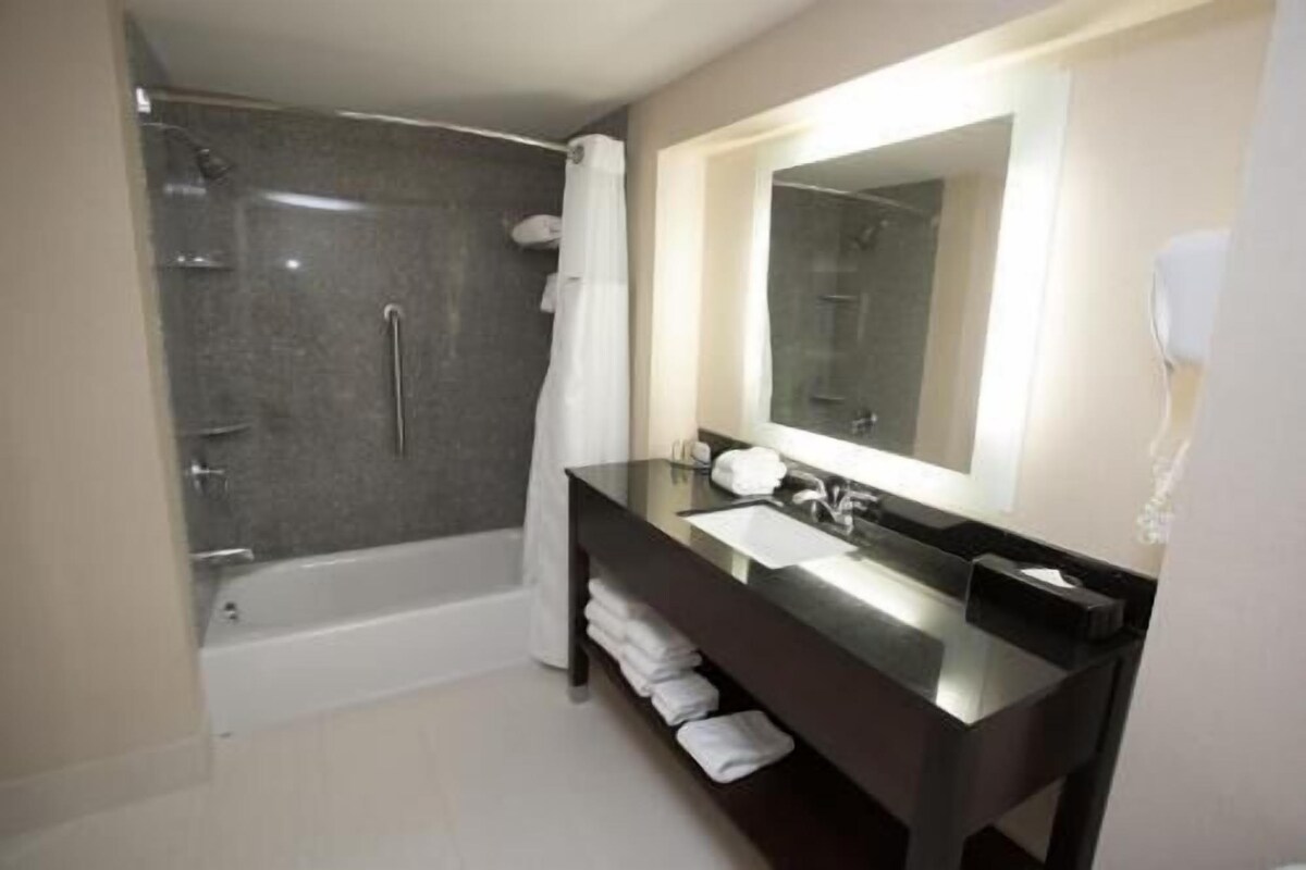Ein Badezimmer mit Dusche, Waschbecken, Spiegel und Handtuchhalter.