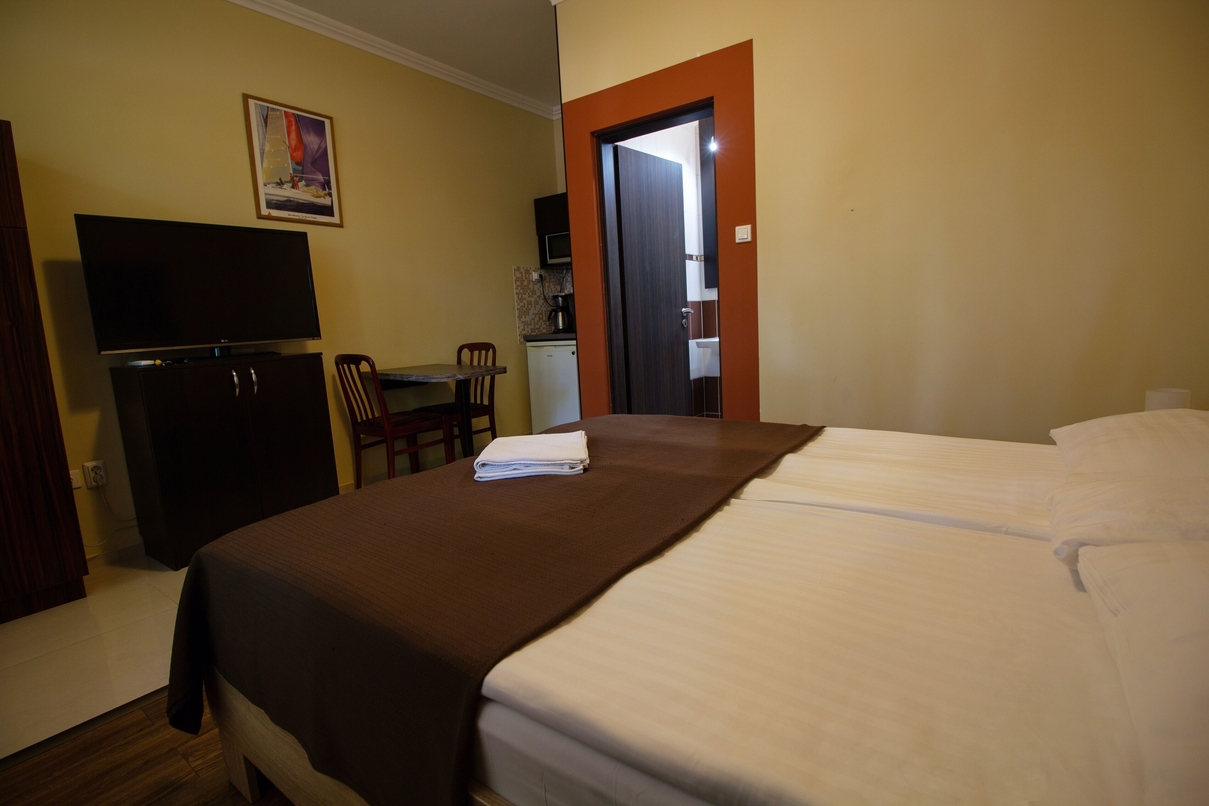 Habitación de hotel con cama, escritorio con silla, televisión y puerta que da a un baño.