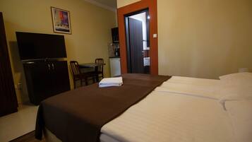 Habitación de hotel con cama, escritorio con silla, televisión y puerta que da a un baño.