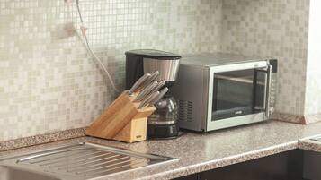 A kitchen with a microwave, coffee maker, and knife block on the counter.