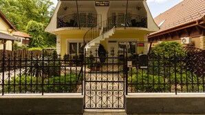 A two-story building named Bella Villa with a balcony on the upper floor, a staircase leading to the entrance, and a gated entrance with a wrought iron fence. - Bella Villa Siofok (Siófok)