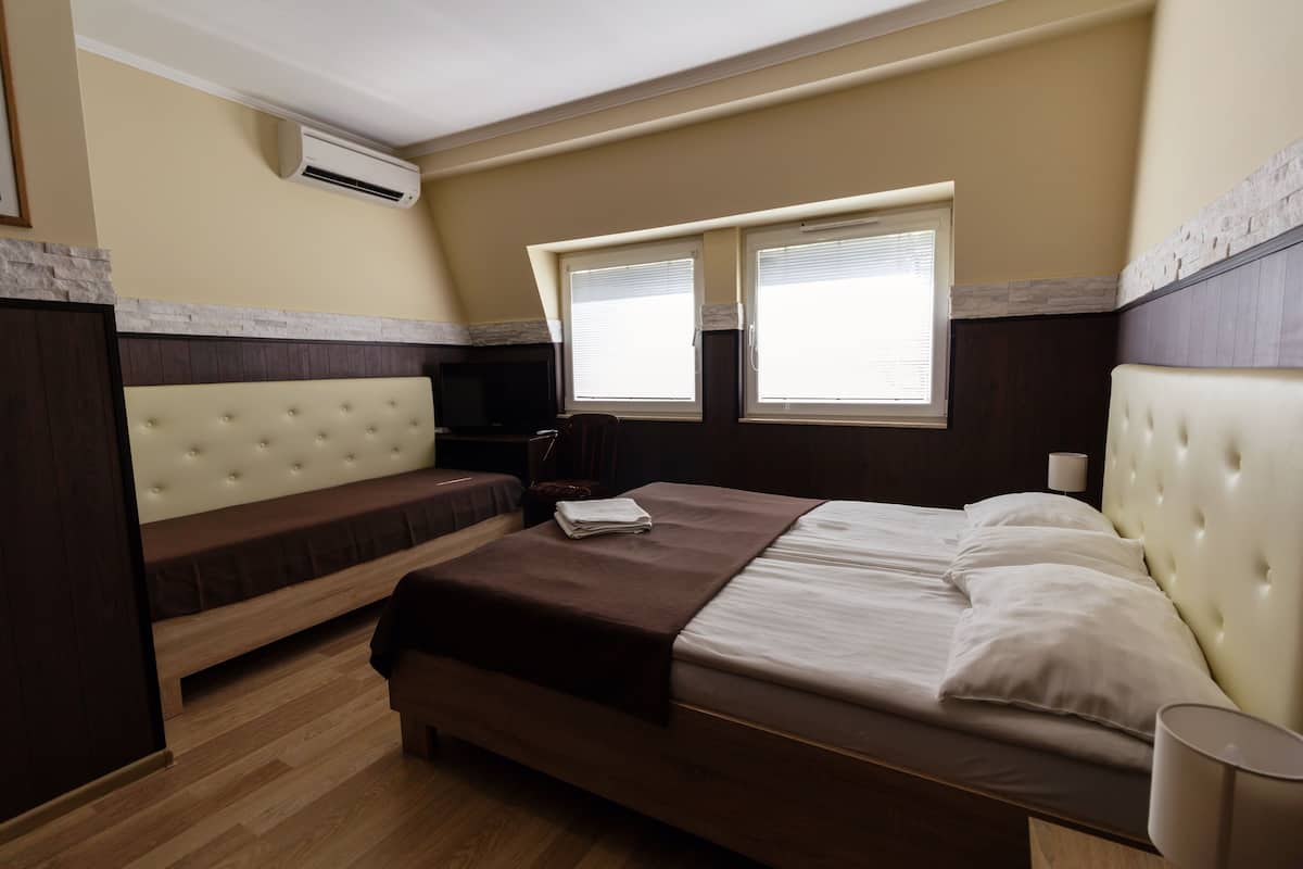 Ein Schlafzimmer mit einem Bett, einer Bank, einem Schreibtisch und einer Klimaanlage.