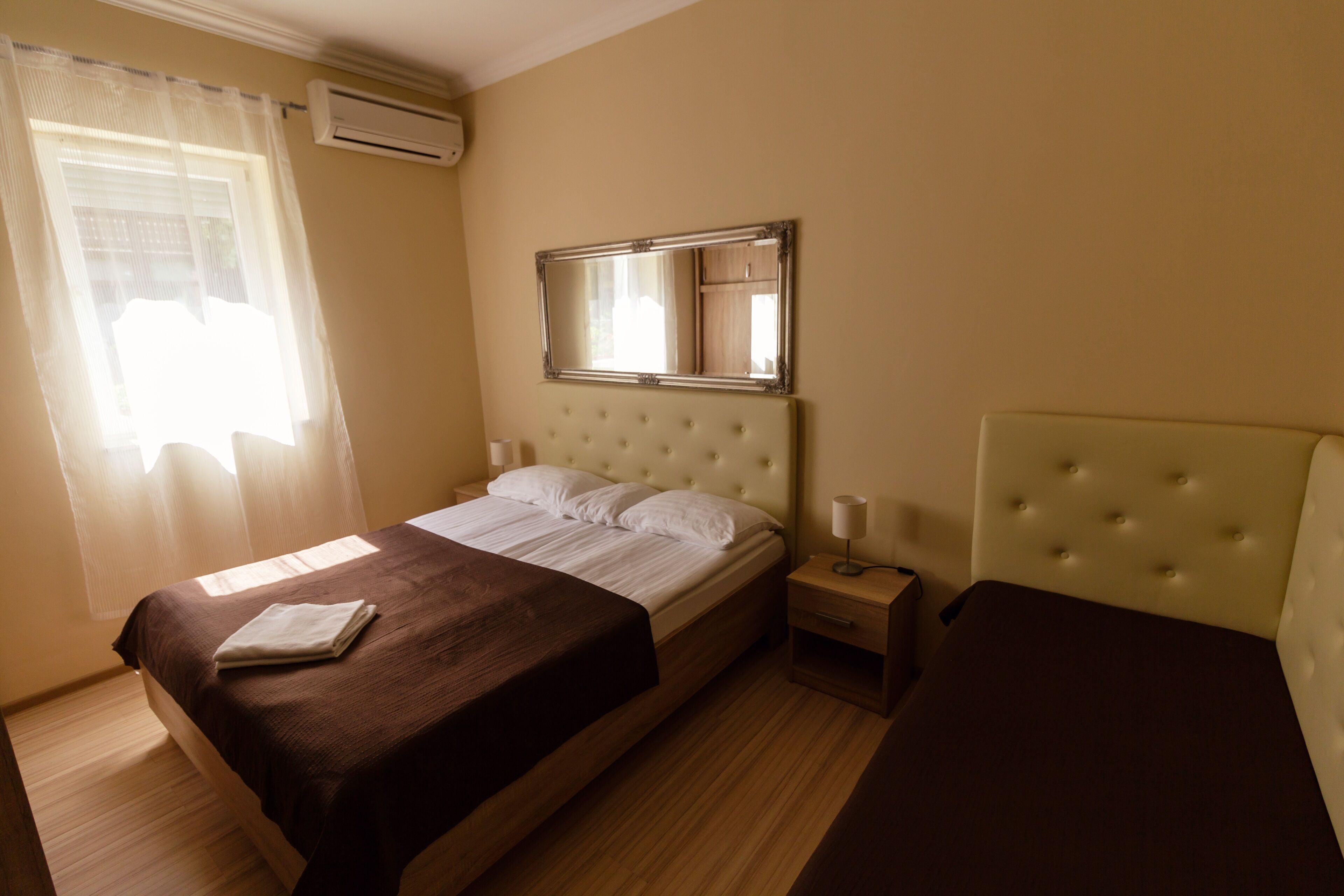 Una camera d'albergo con un letto, un comodino e uno specchio.