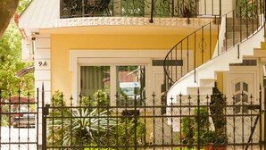 A two-story building with a yellow facade, a black wrought iron fence, and a staircase. - Bella Villa Siofok (Siófok)