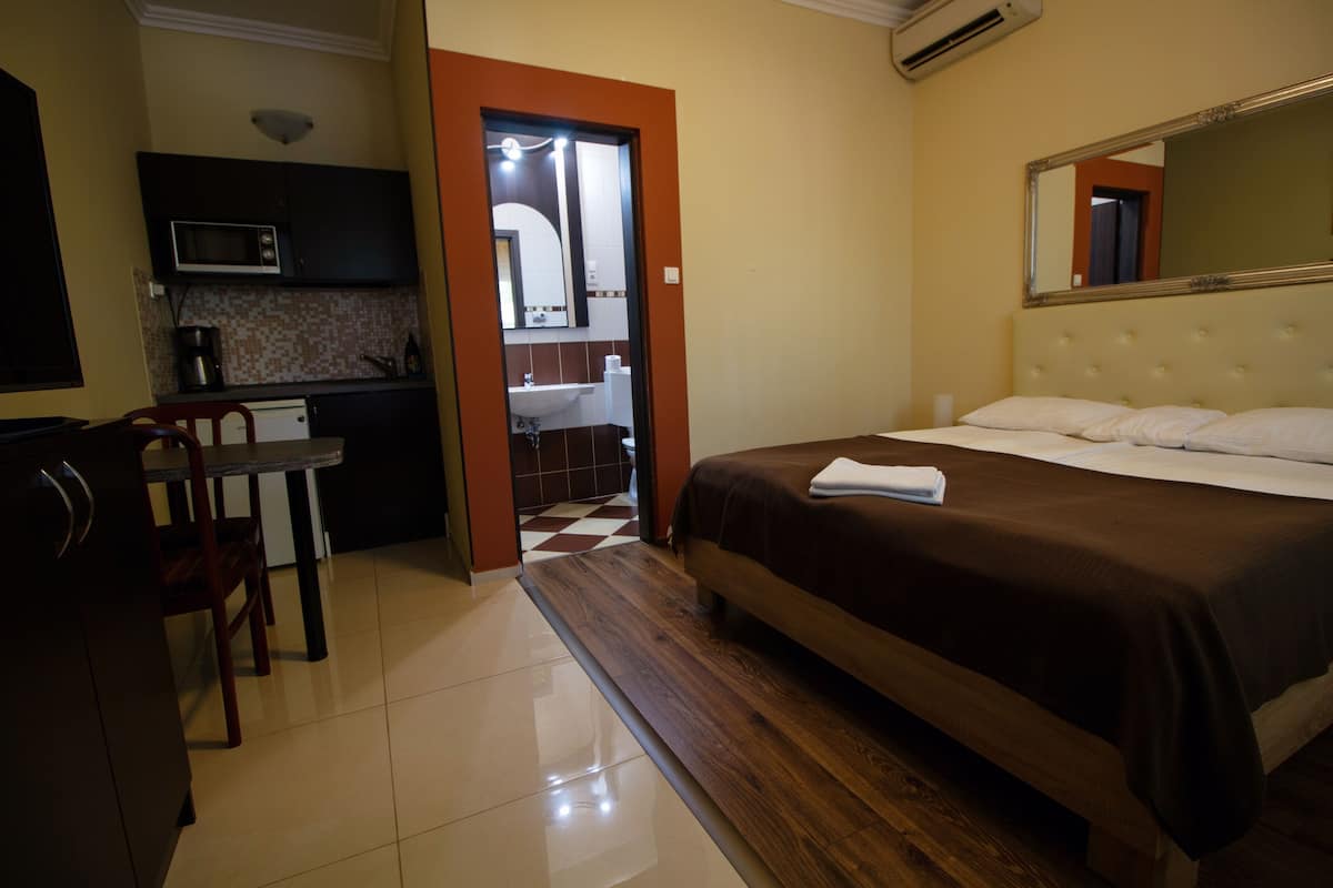 Ein Hotelzimmer mit Bett, Schreibtisch, Stuhl, Mikrowelle, Spüle und Spiegel.