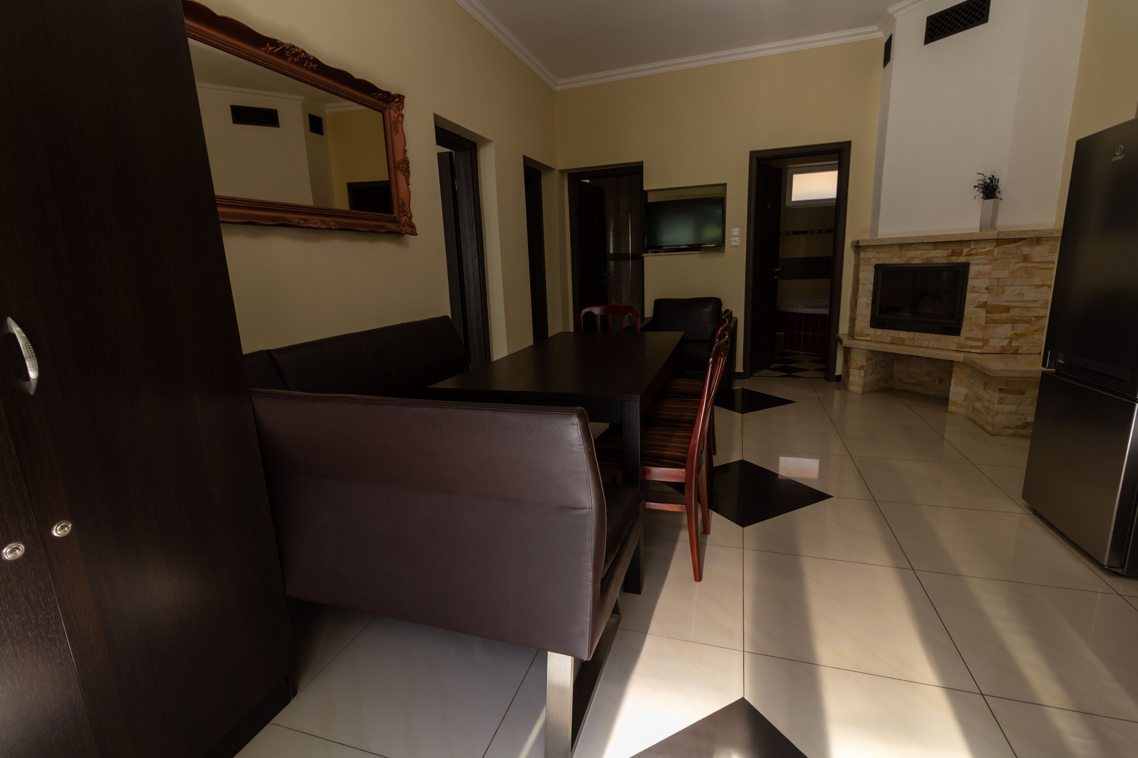 A modern kitchen with a dining area, a fireplace, and a TV mounted on the wall.