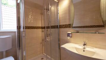 A modern bathroom with a glass-enclosed shower, a white sink, and a tiled backsplash.