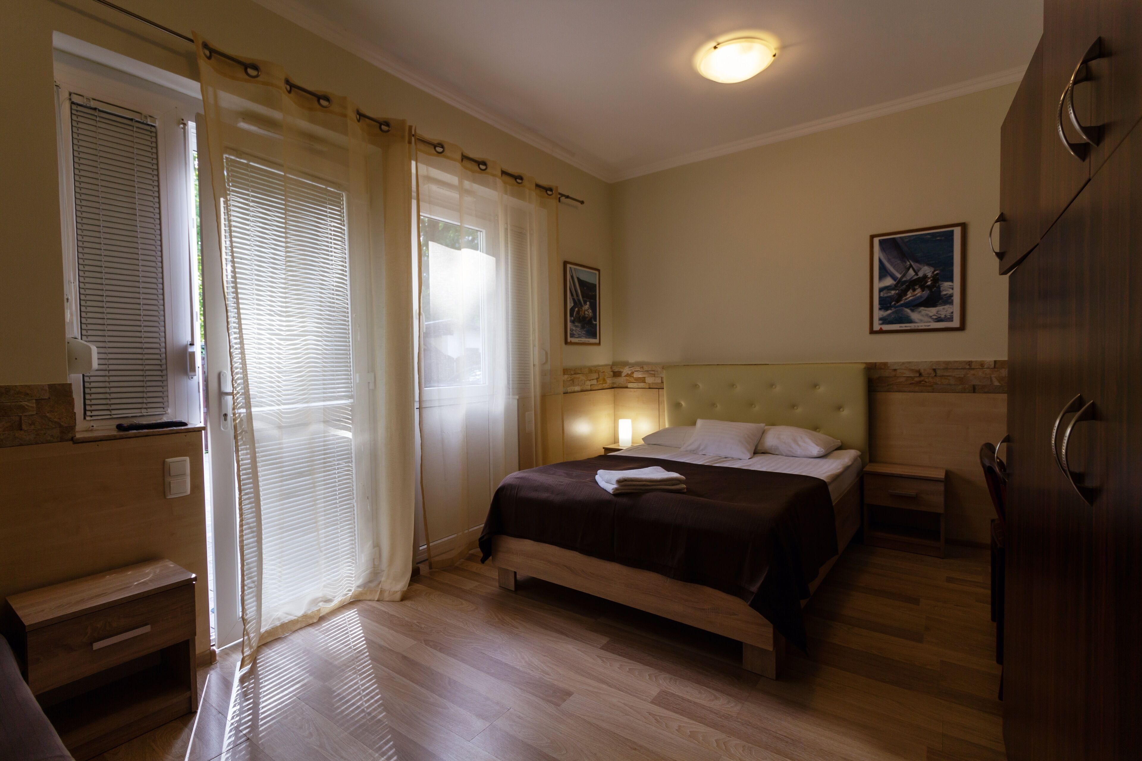 A bedroom with a bed, a nightstand, a dresser, and a window with blinds.