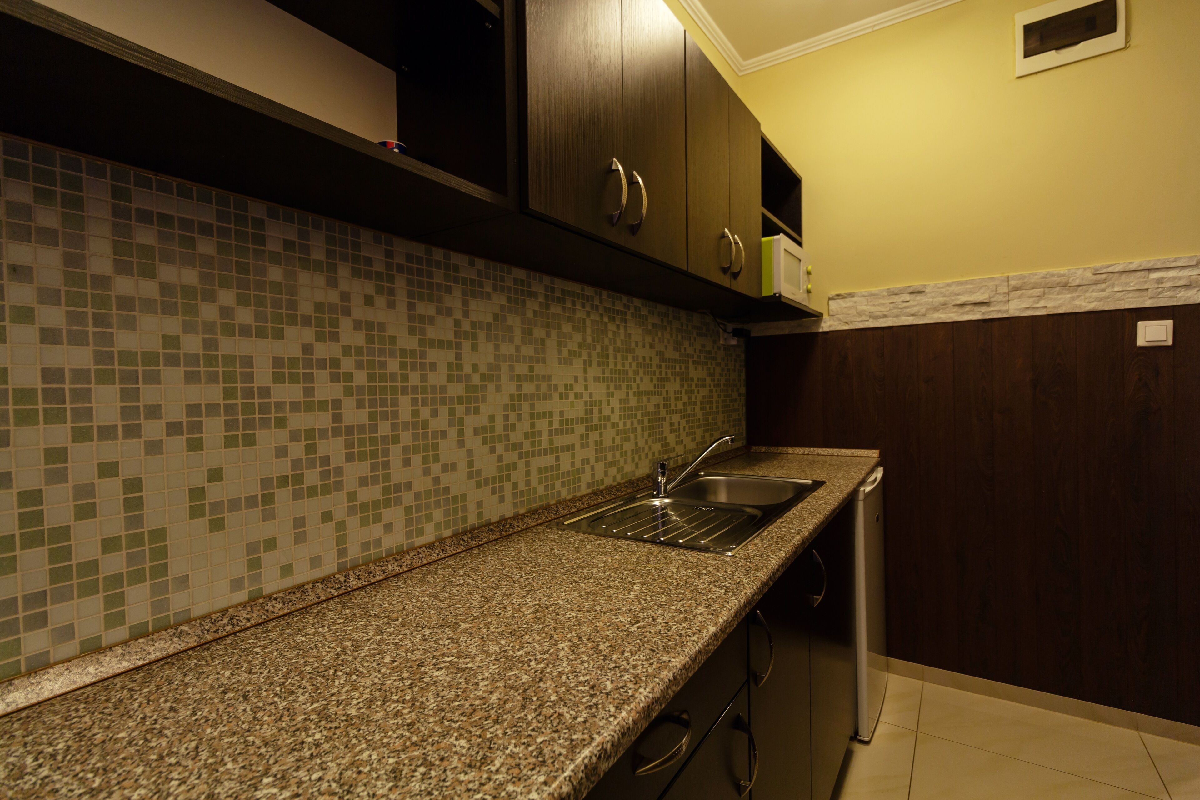 A kitchen with a granite countertop, a sink, and wooden cabinets.