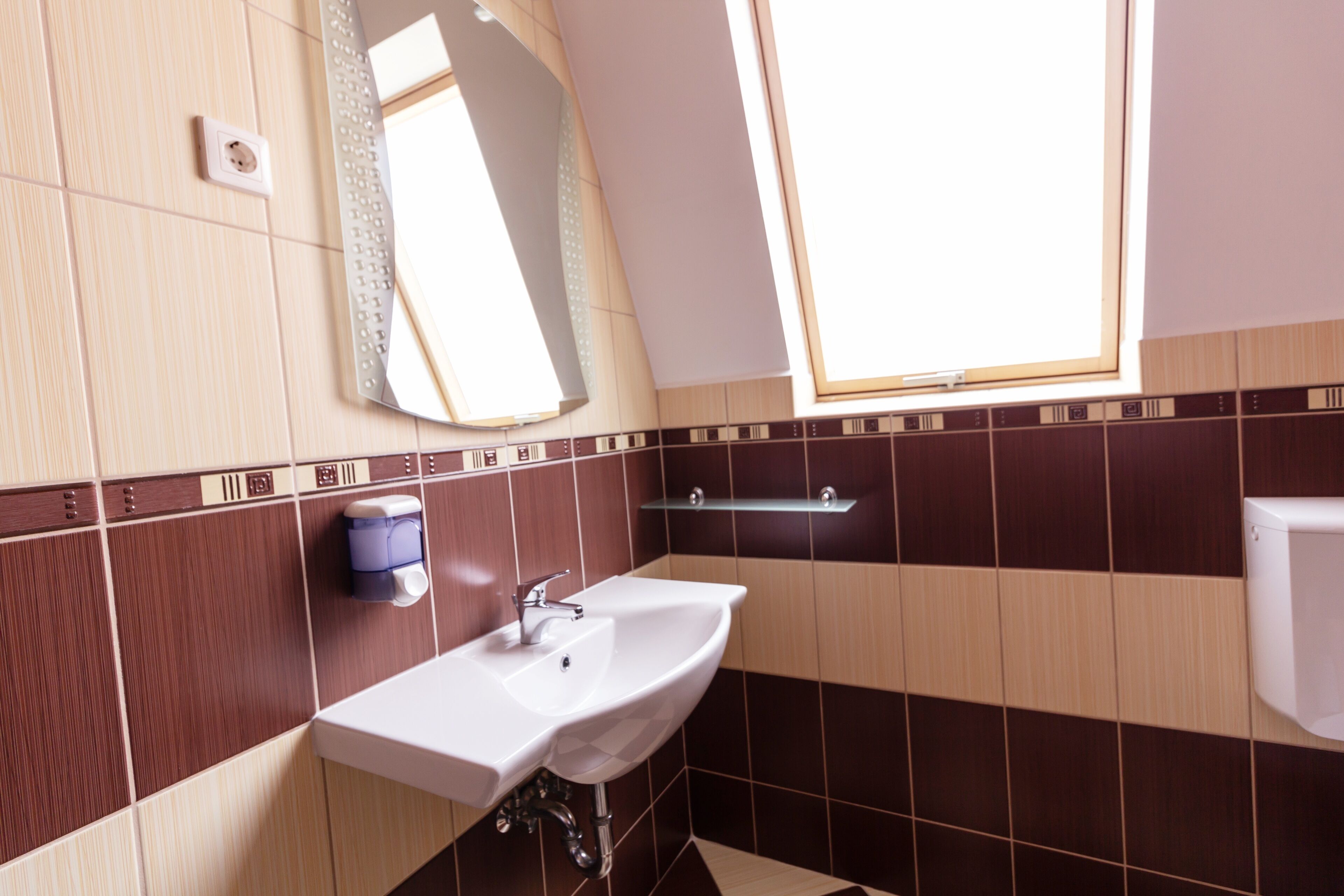 Une salle de bain moderne avec un lavabo blanc, un miroir et une fenêtre.