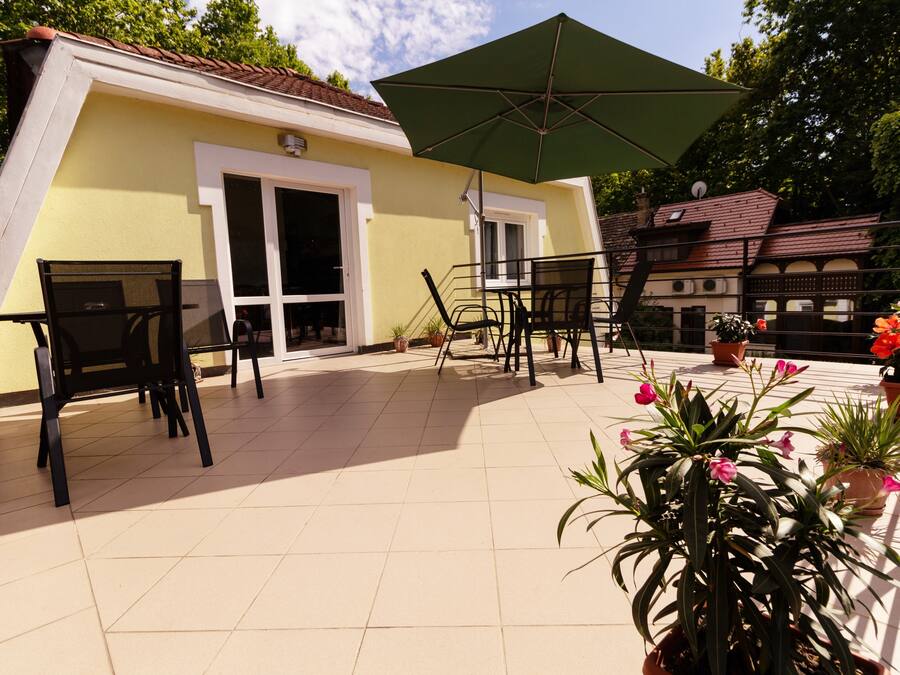 A patio area with outdoor seating, a green umbrella, and potted plants.