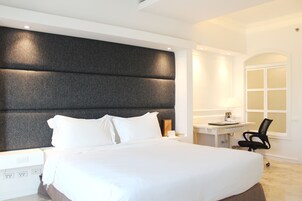 Una habitación de hotel moderna con una cama grande, un escritorio con silla y una ventana.