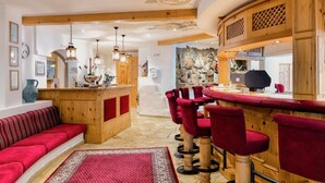 A cozy interior with a wooden bar area, red upholstered seating, and a stone wall backdrop. - Hotel Appartement Similaun (Soelden)