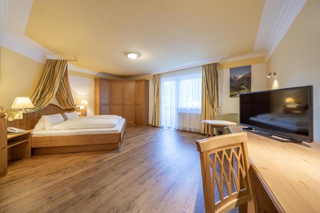 Ein Hotelzimmer mit Bett, Fernseher, Schreibtisch und Stuhl.
