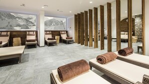 A spa room with massage tables, wooden partitions, and a large window with a mountain view. - Hotel Appartement Similaun (Soelden)