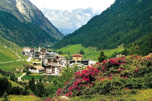 A mountain village with traditional buildings, a valley, and blooming flowers. - Hotel Appartement Similaun (Soelden)