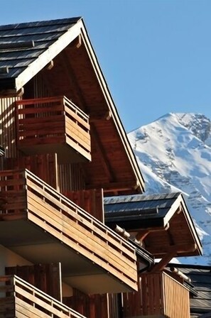 A wooden chalet with balconies, set against a snowy mountain backdrop. - Les Terrasses du Soleil d'Or (Les Orres)