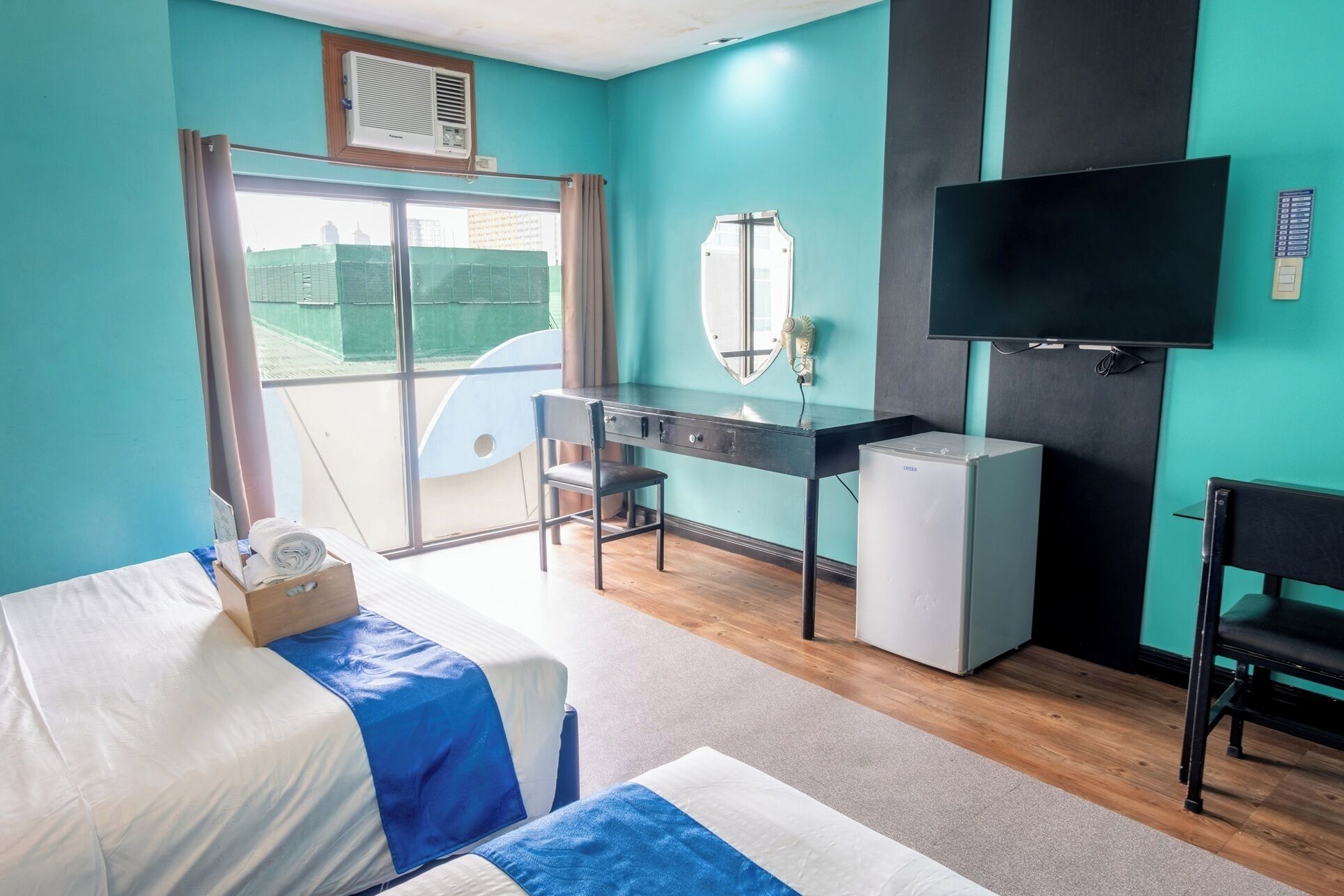 Ein Hotelzimmer mit Bett, Schreibtisch, Stuhl, Fernseher und kleinem Kühlschrank.