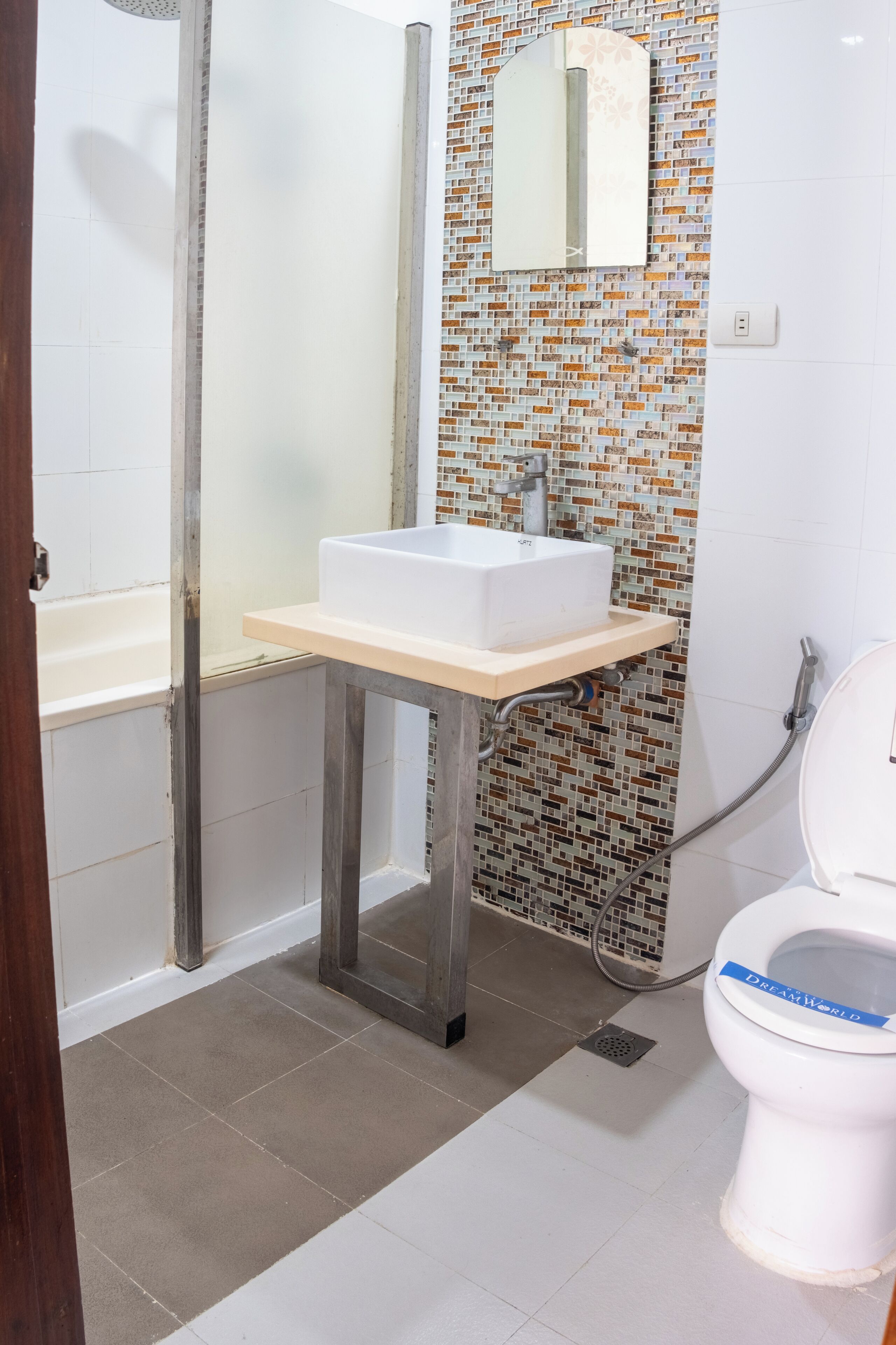 A bathroom with a white sink, a mirror, a shower, and a toilet.