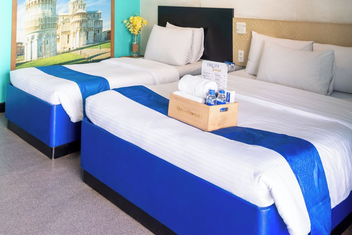 Habitación de hotel con dos camas, un ventanal con vista a la Torre Inclinada de Pisa y un cabecero con panel de madera.