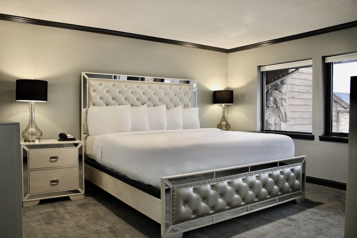 A neatly arranged bedroom with a large bed, bedside tables, and a window with a view.
