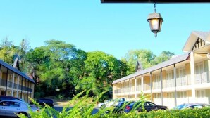 A motel with a row of rooms, a parking lot, and a hanging lamp.