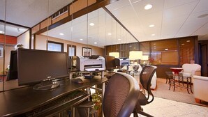 A modern office space with a large desk, multiple printers, and comfortable seating.