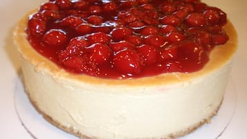 Un pastel de queso coronado con cerezas.