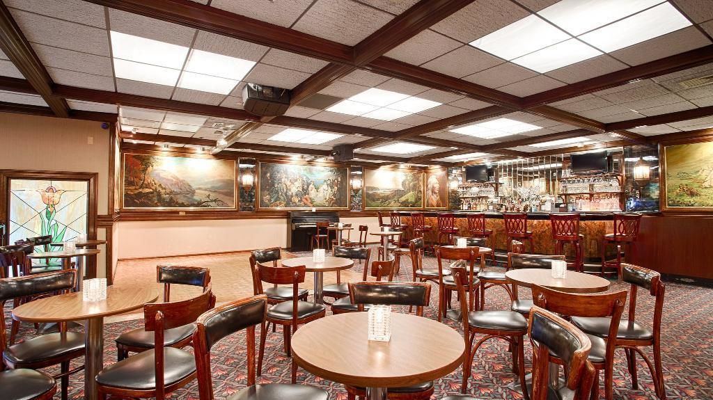 Un restaurante con mesas y sillas redondas, una zona de bar y obras de arte en las paredes.
