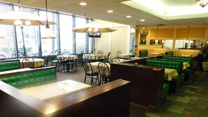 A restaurant with booths and tables, large windows, and a tiled floor.