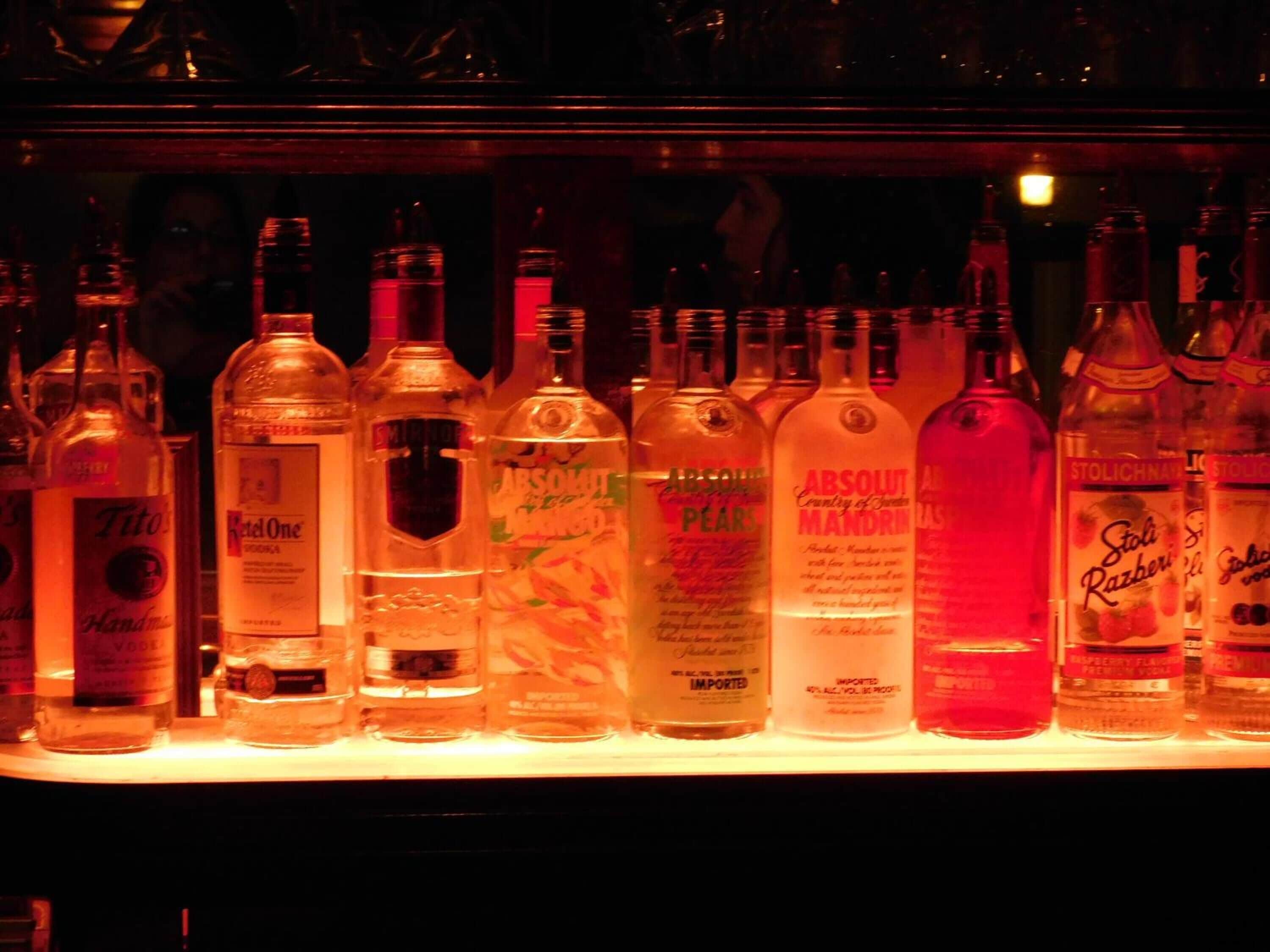 A bar with various bottles of alcohol including brands like Tito's, Ketel One, Smirnoff, and Absolut.