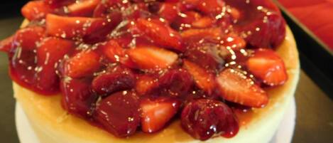 A dessert with a creamy base topped with sliced strawberries and a glossy red sauce.