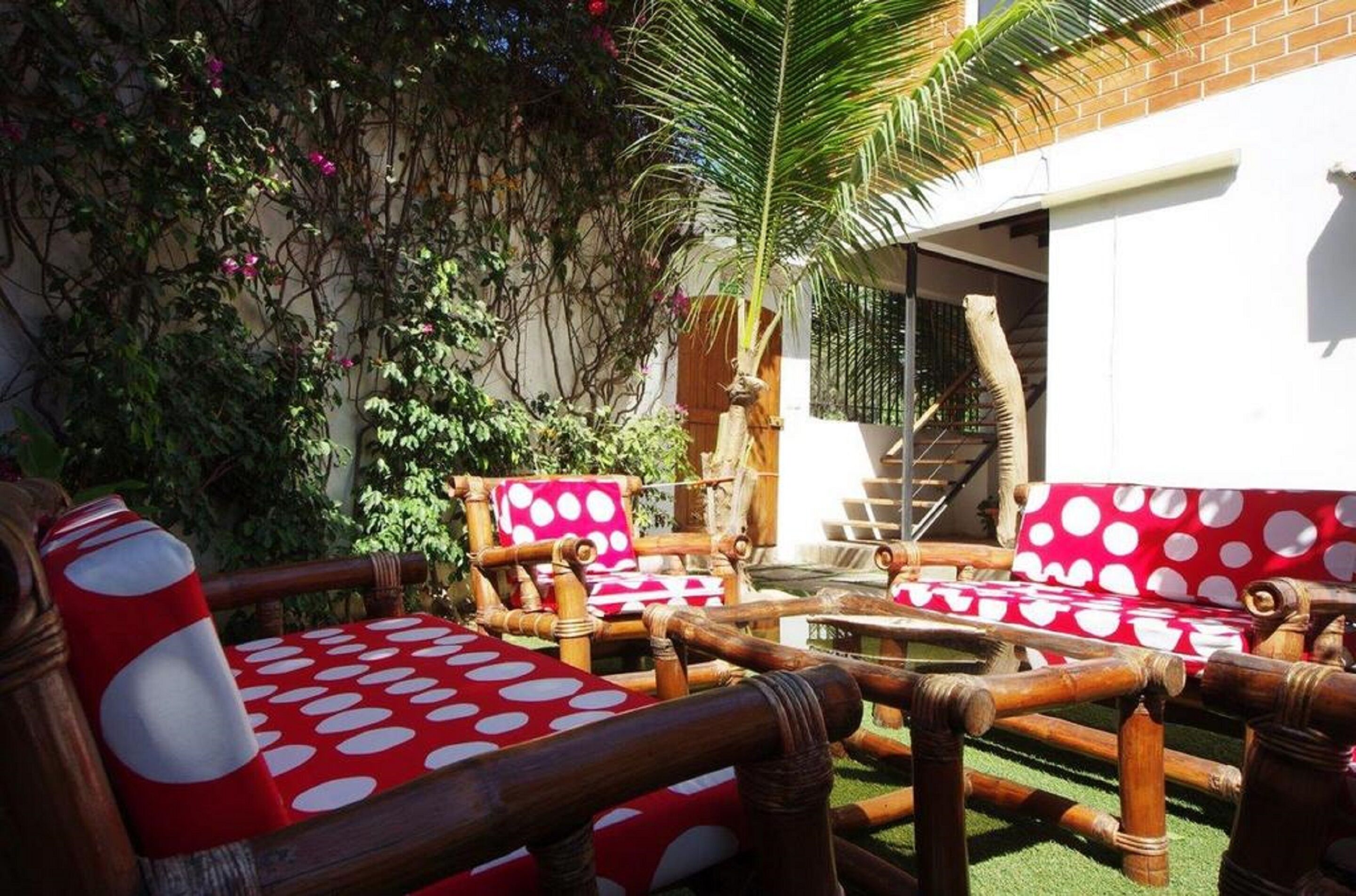 A patio area with wooden furniture and a red and white polka dot cushion.