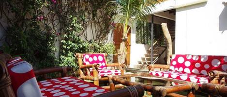 A patio area with wooden furniture and a red and white polka dot cushion.
