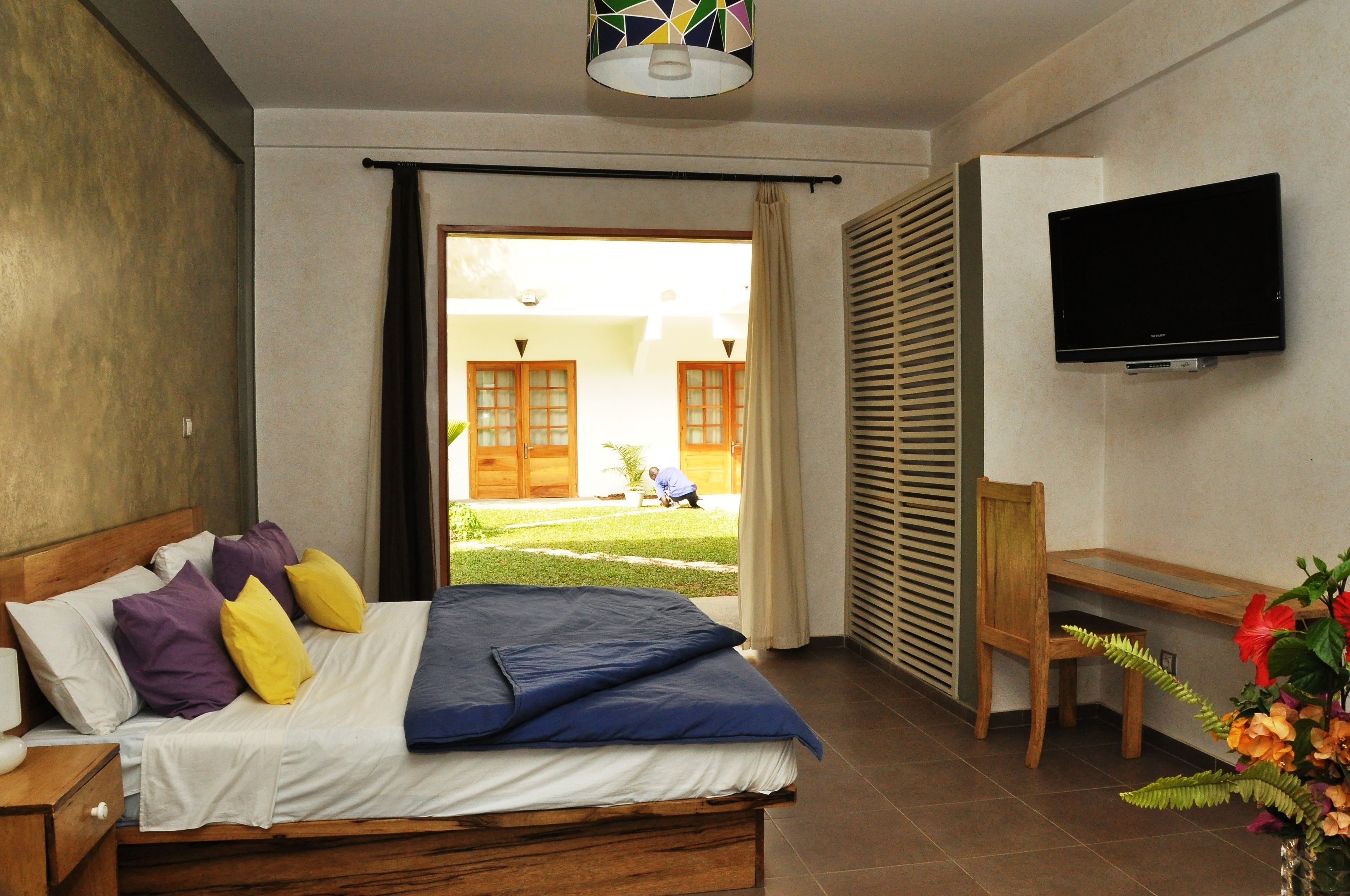 A bedroom with a bed, a desk, a chair, and a TV.