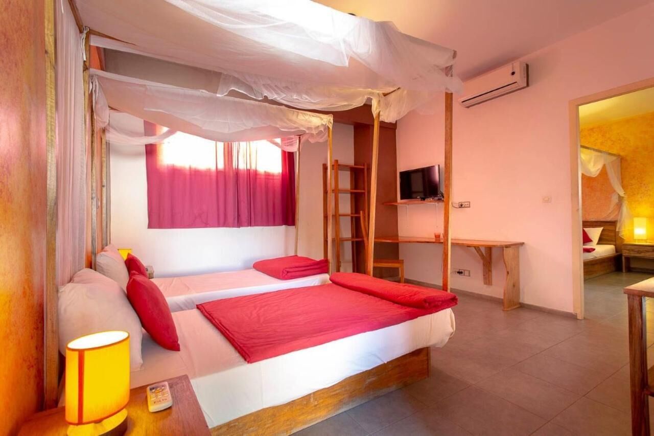 Ein Zimmer mit einem Bett, einem Fernseher, einem Schreibtisch und einem Sessel.