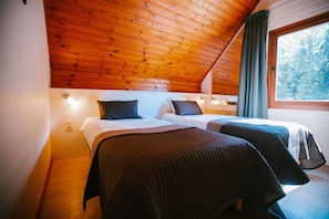 Habitación con dos camas, techo de madera y ventana con cortinas.
