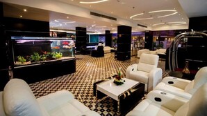 A modern lobby with a checkered floor, a large aquarium, white sofas, and a coffee table. - JUFFAIR GATE HOTEL (Manama)