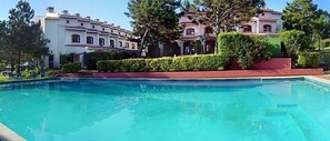 Una piscina al aire libre, sombrillas, sillones reclinables de piscina