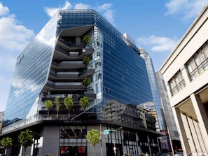 A modern glass building with a unique angular design, featuring multiple balconies and a visible storefront at the base. - Guide Hotel Taoyuan Fuxing (Taoyuan City)