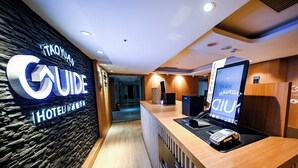 Et hotelreceptionsområde med en stenvæg, en receptionsdisk, et digitalt skærm og et skilt, der angiver, at det er et 'TAOYANAN HOTEL'.