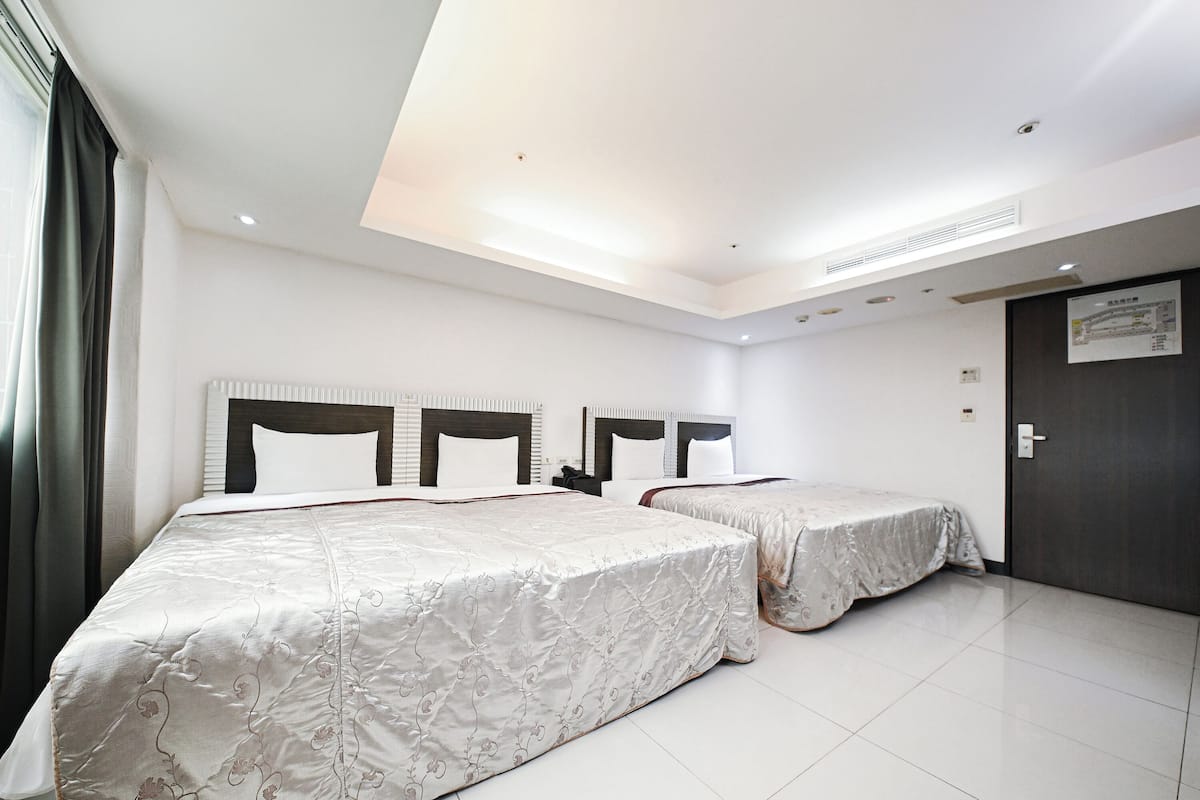 A hotel room with two beds, a dark door, and a white tiled floor.
