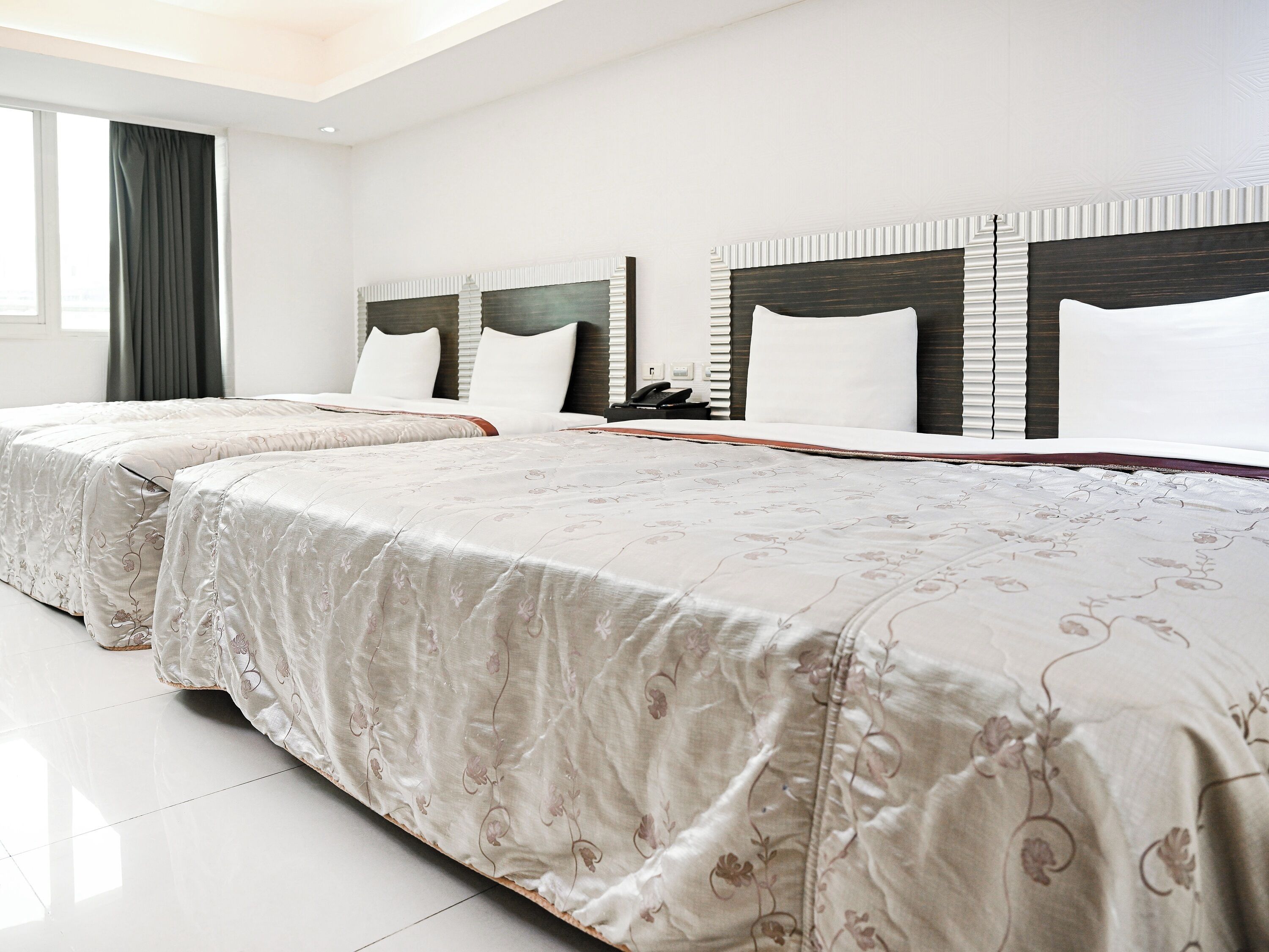 A hotel room with two beds, a large window, and a modern design.