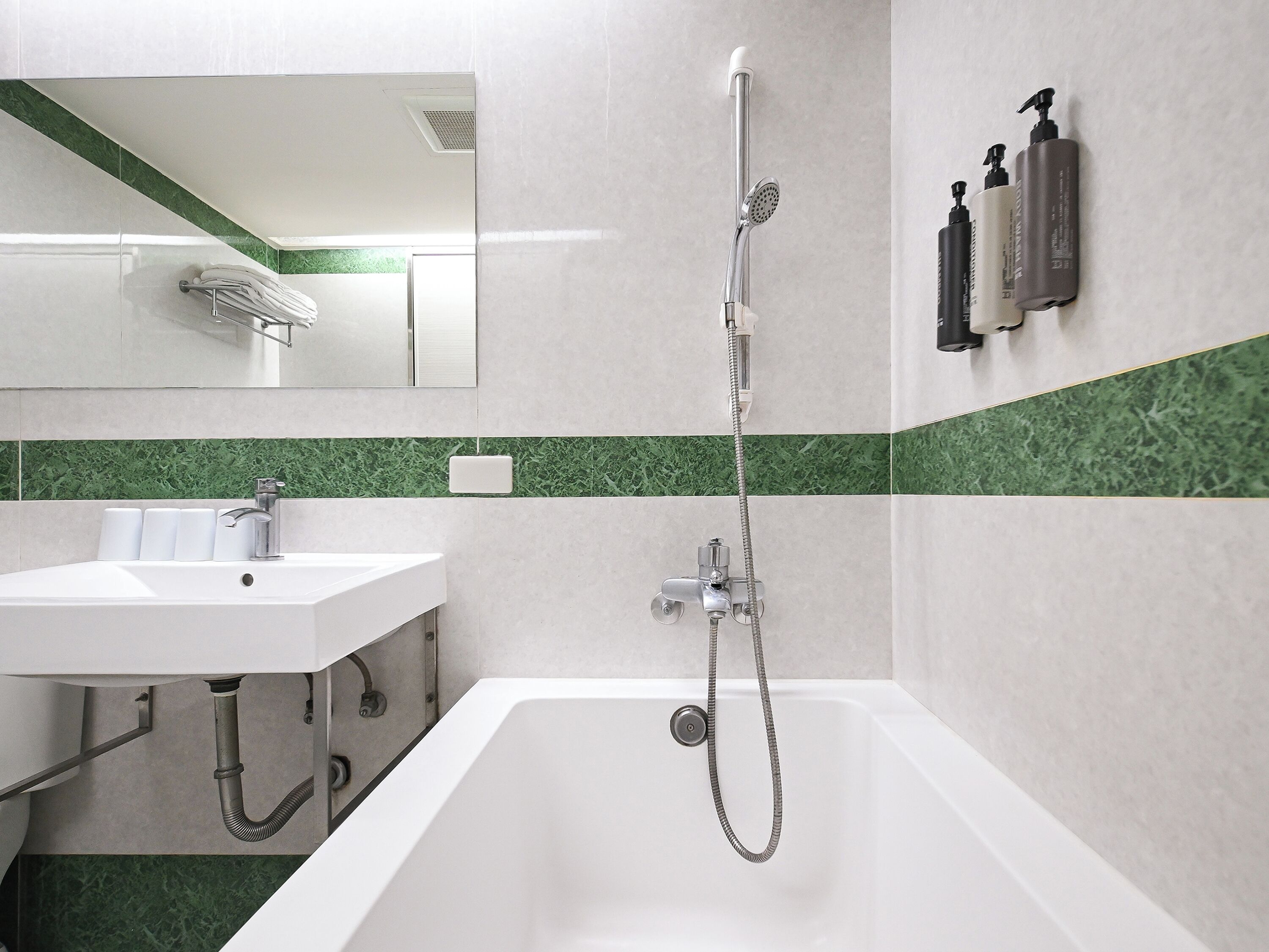 Un baño moderno con bañera, lavabo, espejo y dos dispensadores de jabón en la pared.
