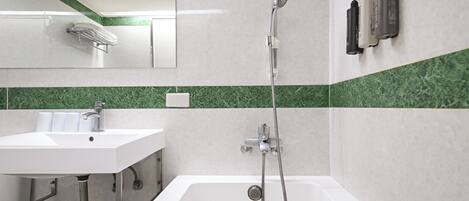 Un baño moderno con bañera, lavabo, espejo y dos dispensadores de jabón en la pared.