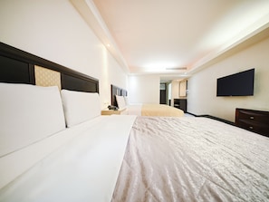 A hotel room with a large bed, a bedside table, a TV mounted on the wall, and a mirror.