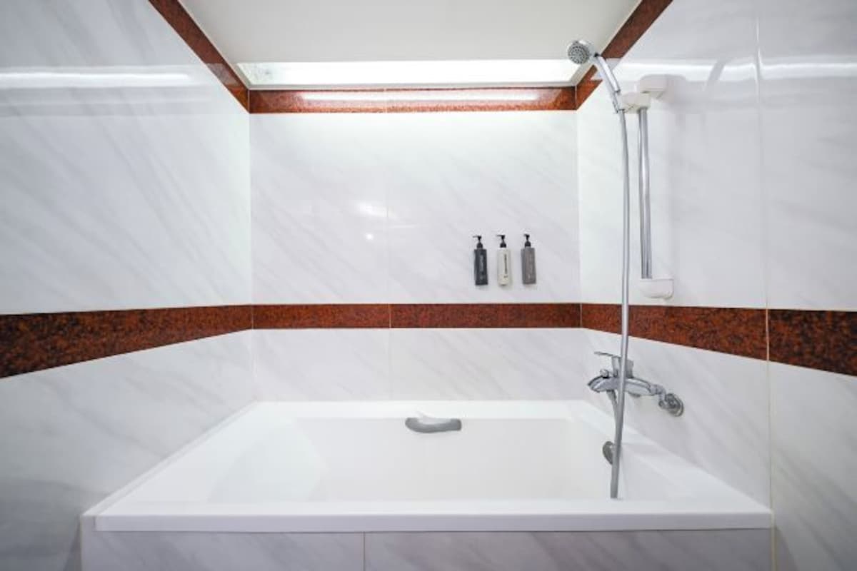A modern bathroom with a white bathtub, a shower, and a wooden ceiling.