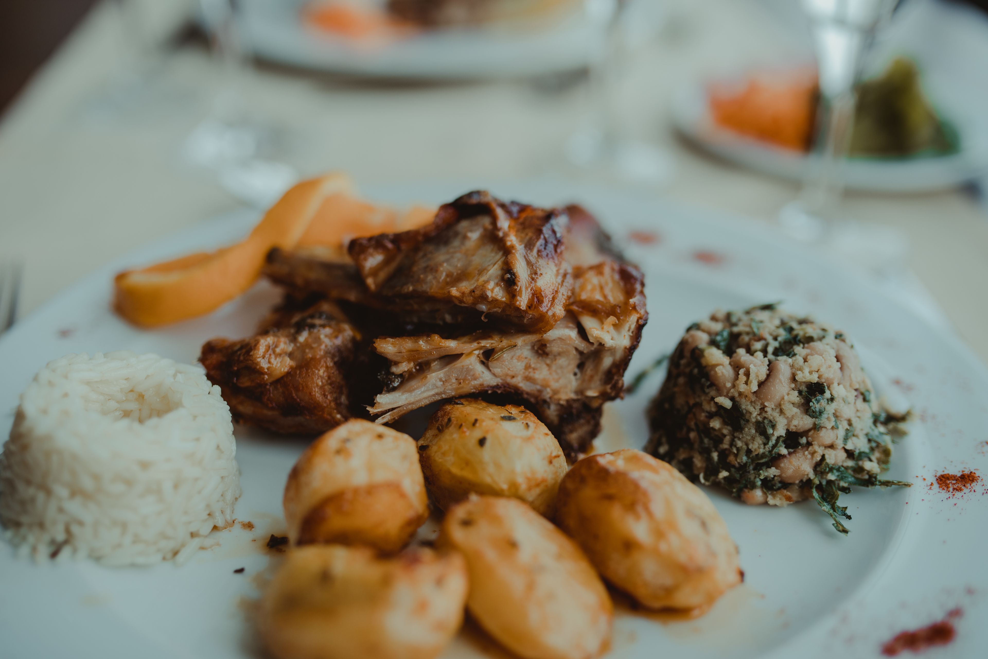 A plate with roasted meat, potatoes, and rice.